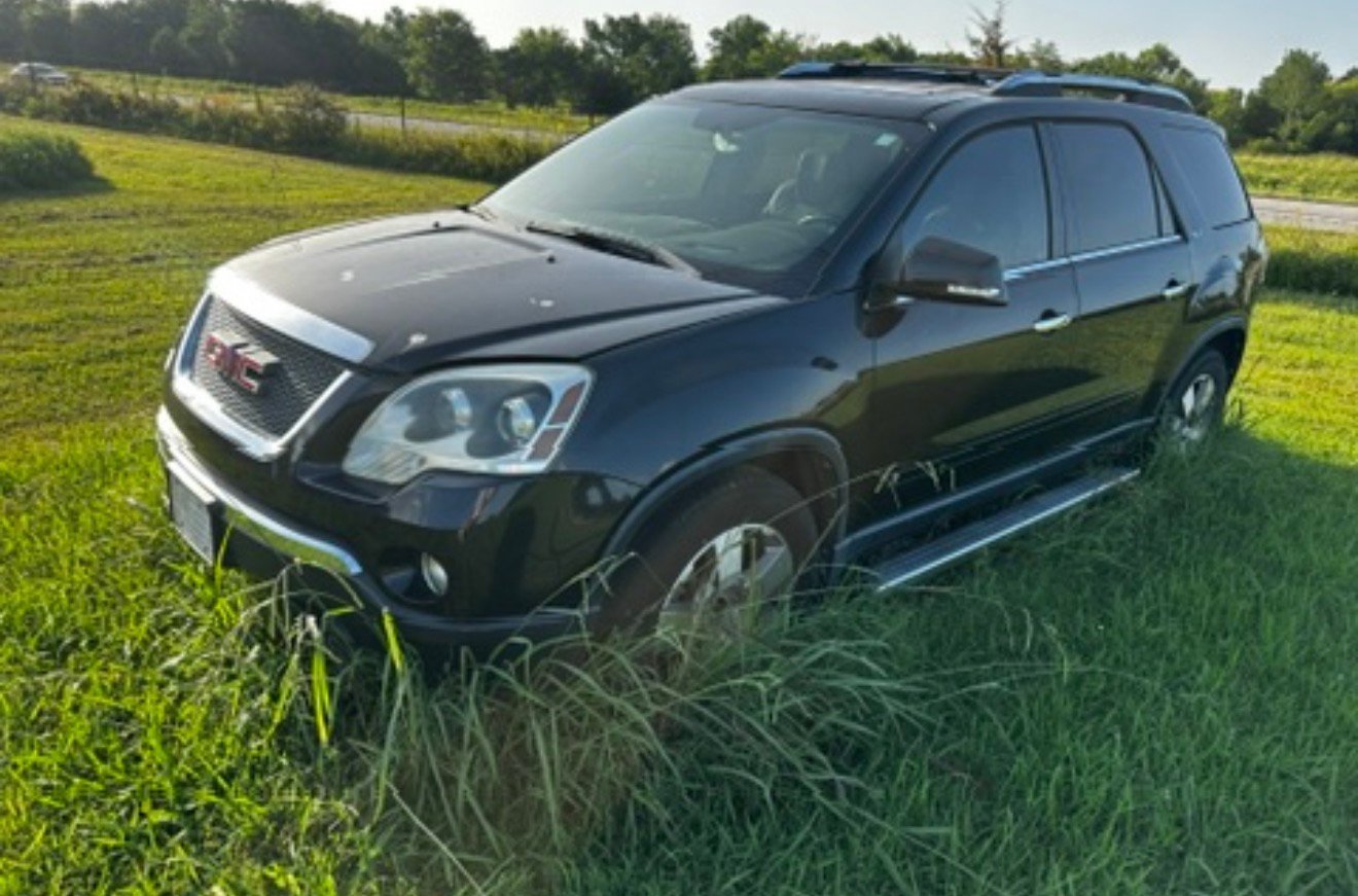 Black GMC SUV parked in tall grass